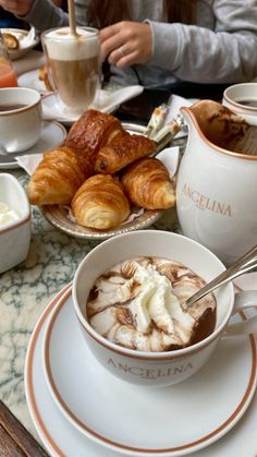 there is a cup of coffee on the table with croissants and pastries