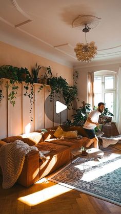 a man sitting on top of a couch in a living room next to a window