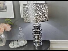 a lamp that is on top of a table next to some vases and flowers