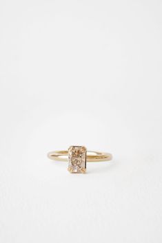 a yellow gold ring with a square shaped diamond in the center, on a white background