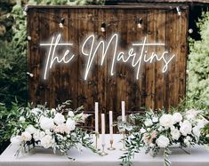 a table topped with flowers and candles next to a sign that says the martinis