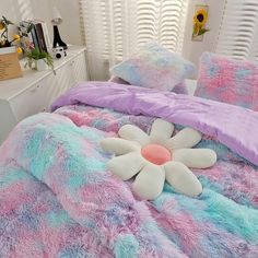 a bed with pink, blue and white comforters on it