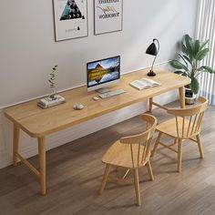 a wooden desk with two chairs and a computer monitor on it, in front of a window