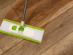 a mop is laying on the floor with a green and white duster next to it