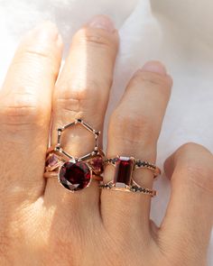 a woman's hand with two rings on top of each other and one has a red stone in the middle