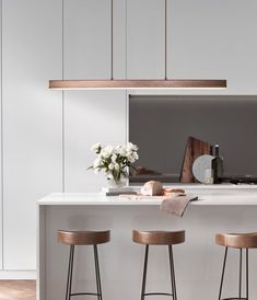 three stools are sitting at the bar in this modern kitchen with white walls and wood flooring