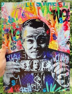 a person holding up a piece of art with graffiti on it