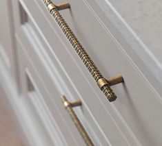 two brass handles on a white cabinet door