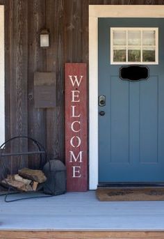 a welcome sign sitting next to a blue door on a wooden porch with a fire hydrant