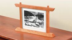 a wooden frame with a black and white drawing on the front is sitting on a table