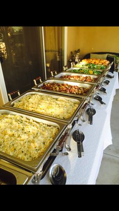 several trays of food are lined up on a buffet table