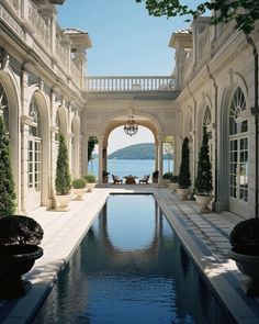 an outdoor swimming pool in the middle of a large building with columns and arches on either side