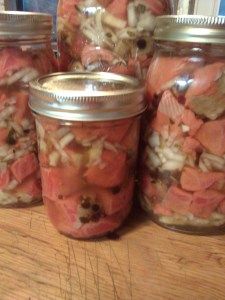 four jars filled with food sitting on top of a wooden table