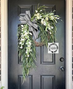 a wreath with white flowers and greenery hangs on the front door