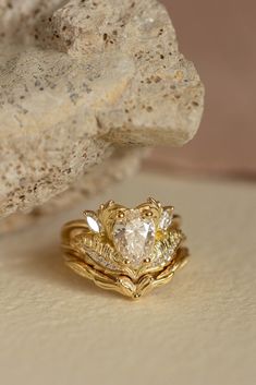 two gold rings with diamonds on them sitting next to a rock