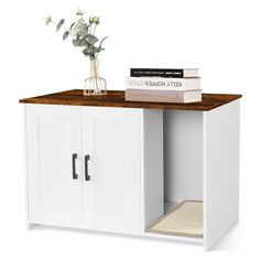 a white cabinet with some books on top and a vase full of flowers next to it