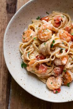 pasta with shrimp and tomato sauce in a white bowl on a wooden table, ready to be eaten