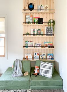 a green couch sitting in front of a wooden shelf