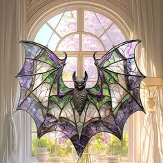 a stained glass bat sitting on top of a table in front of a large window