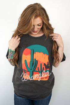 Step into a sunset-soaked desert landscape with the Wrangler Retro® Graphic Tee. This oversized fit T-shirt for women combines vintage vibes with modern comfort. Made from soft, 100% cotton in a rich Chocolate Torte shade, this tee features a striking front graphic of a serene desert scene, complete with a towering cactus and a silhouette of a cowboy on horseback. The design is framed by a warm, vibrant orange and red sunset under a large round motif, adding a touch of Western nostalgia to your Chocolate Torte, Desert Scene, Red Sunset, Retro Graphic Tees, Fall Days, Desert Landscape, T Shirt For Women, Vibrant Orange, Sweater Blouse