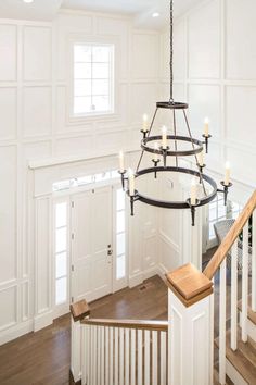 a chandelier hanging from the ceiling in a room with white walls and wood floors