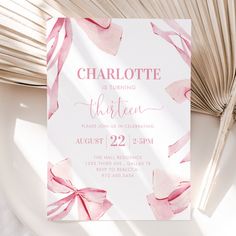 a pink and white birthday party card on a plate with palm leaves in the background