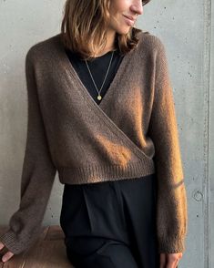 a woman wearing a brown sweater and black pants