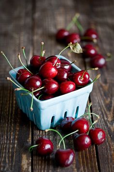 cherries in a blue bowl on a wooden table