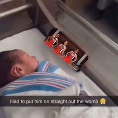 a baby laying in a crib next to an ironing board with pictures on it