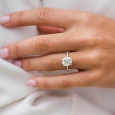 a woman's hand wearing a ring with a diamond in the middle and a white background