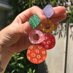 a person holding three different colored earrings in their hand, one with an animal earring and the other with donuts on it