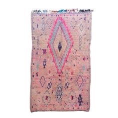 a pink rug with an intricate design on the front and back, in different colors