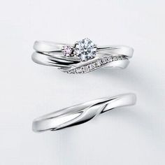 two white gold wedding rings with pink and white diamonds on each band, set against a plain background