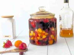 a jar filled with fruit sitting on top of a table next to a wooden spoon