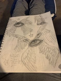 a person holding a notebook with drawings on it and an owl in the middle is sitting down