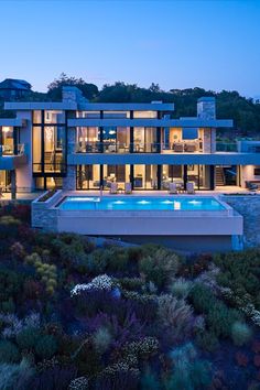 an aerial view of a modern house with pool and landscaping in the foreground at dusk