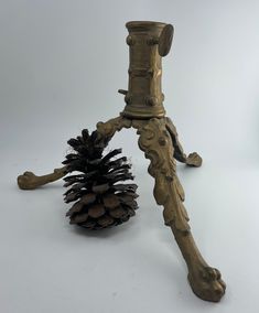 an old brass candle holder with a pine cone on it