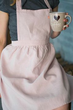 a woman in an apron holding a coffee cup