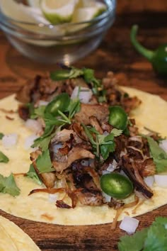 a tortilla topped with meat and veggies on top of a wooden table