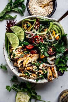 a white bowl filled with chicken and veggies on top of a marble table