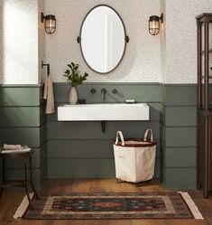 a white sink sitting under a round mirror in a bathroom next to a wooden floor