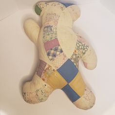 a teddy bear made out of patchwork material on a white surface with no background