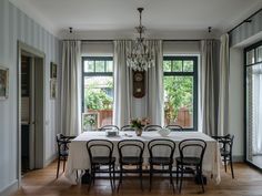 a dining room table with chairs and a chandelier hanging from it's ceiling