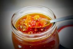 a jar filled with jelly sitting on top of a table next to a metal spoon