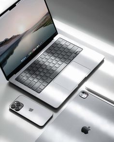 an open laptop computer sitting on top of a white table next to a silver phone