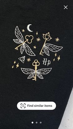 the back of a black shirt with white and gold embroidered designs on it's chest