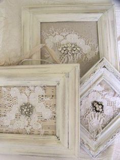 three white frames with lace doily and flowers in them on top of a table