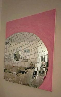 a mirror that is on the wall in front of a pink and white tile background