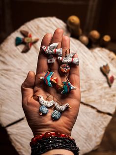 a person's hand holding several rings in front of a wooden table with ornaments on it