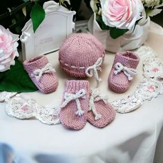 there is a pink knitted hat, booties and baby shoes on the table